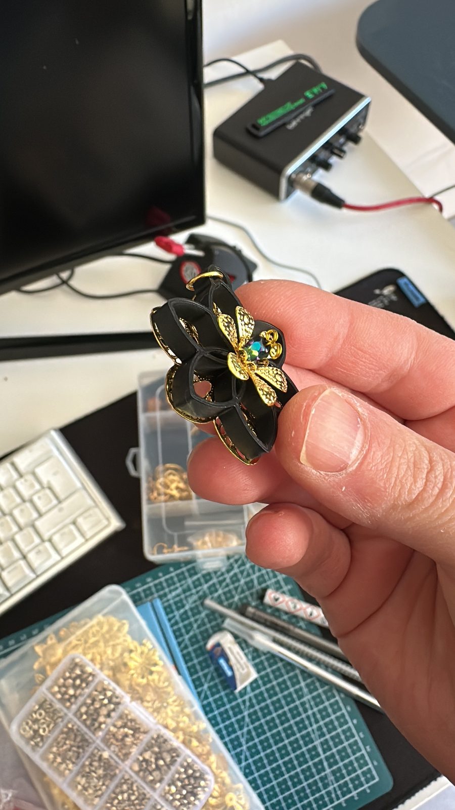 Schwarze 3D-gedruckte Blüte mit goldenen Ornamenten in der Hand