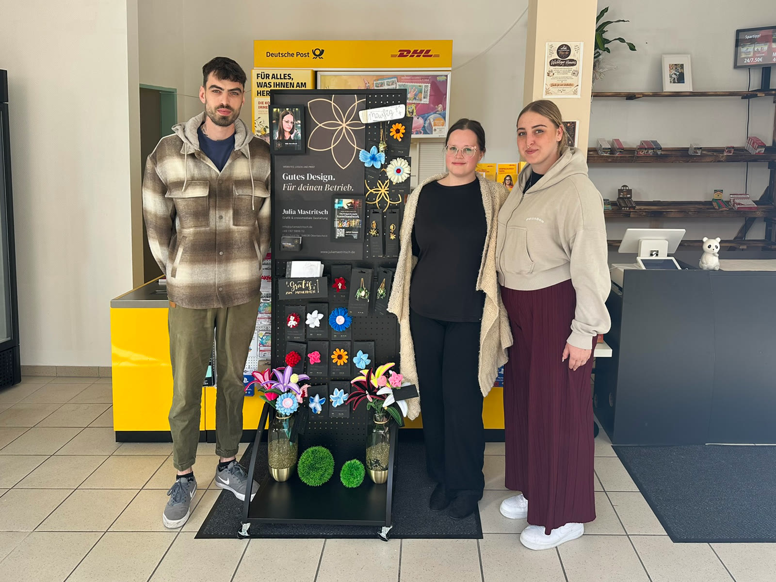 Kevin, Julia und Angelina stehen neben dem Display im Neuerburger Treffpunkt